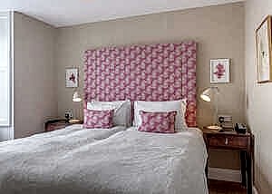 Cozy bedroom with a pink patterned headboard and matching pillows, two nightstands.
